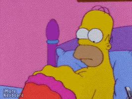 homer simpson is laying in a bed with a pink blanket