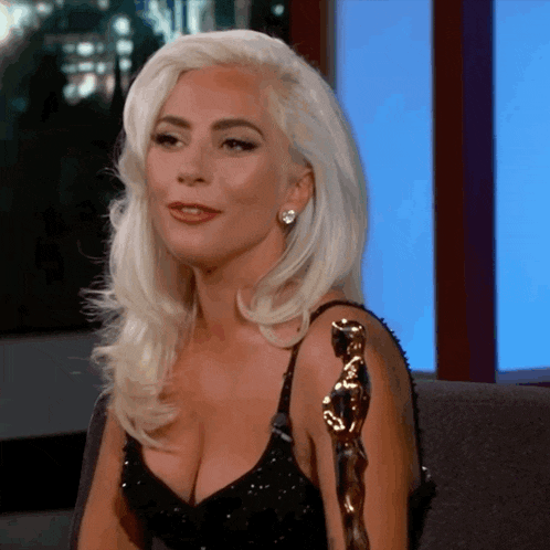 lady gaga is sitting in a chair with a statue on her shoulder