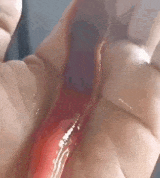 a close up of a person 's hand holding a red liquid .
