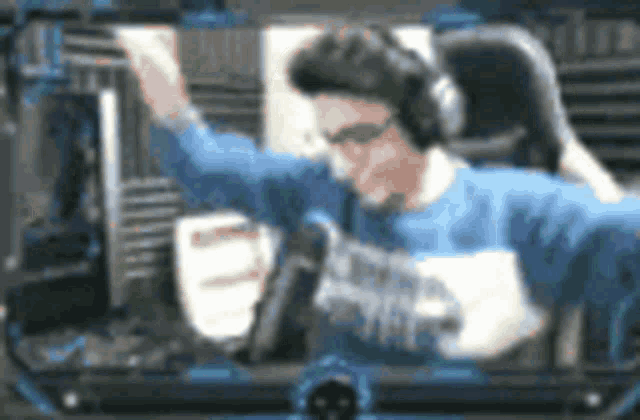 a man wearing headphones is sitting in a chair with his arms outstretched while playing a video game .