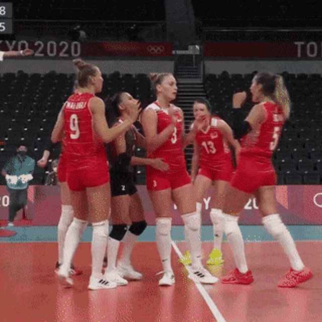 a group of female volleyball players are standing on a court in a stadium .