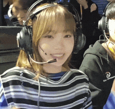 a girl wearing headphones and a shirt that says overwatch smiles