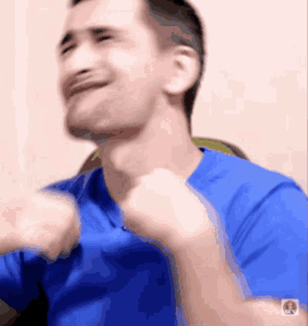 a man in a blue shirt is making a face