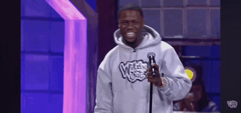 a man in a hoodie is holding a microphone on a stage .