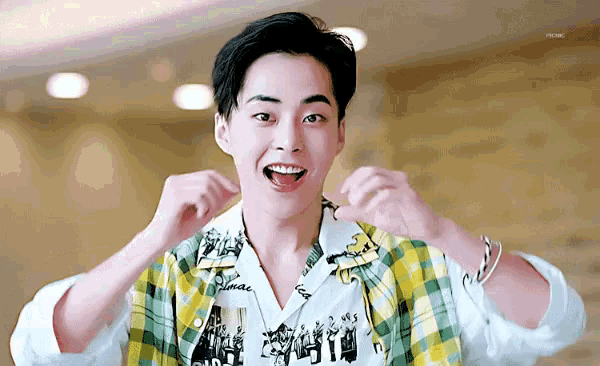 a young man wearing a plaid shirt is making a funny face with his mouth open .