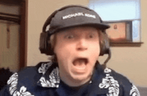 a man wearing headphones and a hat is making a funny face .
