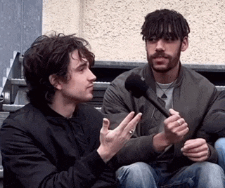 two men are sitting next to each other and one is holding a microphone in his hand