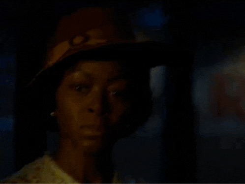 a close up of a woman wearing a hat and pearls .