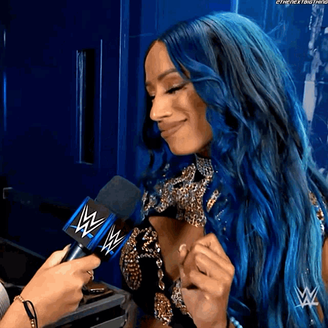 a woman with blue hair is being interviewed by a person holding a microphone that says wwe on it