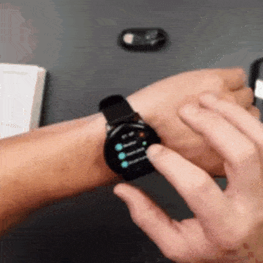 a person is wearing a smart watch on their wrist and pressing a button on it .