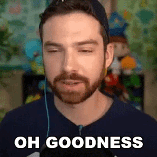 a man with a beard is wearing headphones and making a funny face while saying `` oh goodness '' .