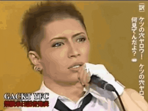 a man is singing into a microphone with gackt yfc on the bottom