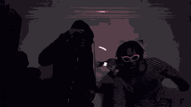 a man in a hoodie is standing in front of a microphone in a dark room .
