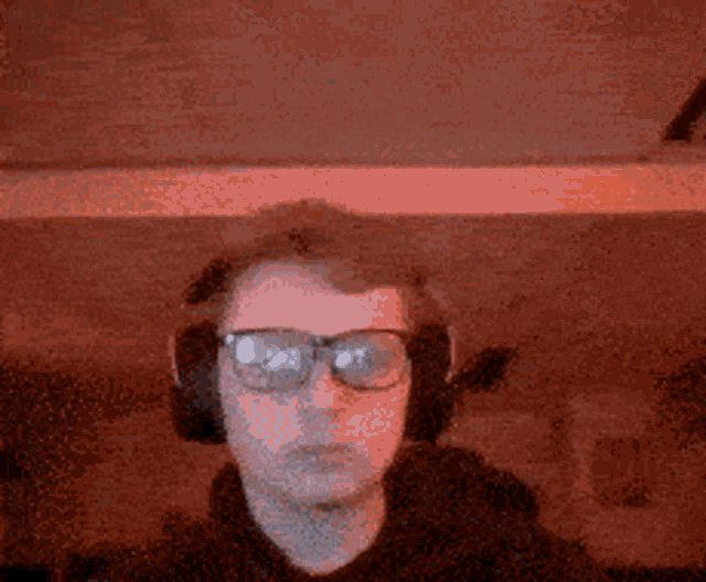 a man wearing headphones and glasses is looking at the camera
