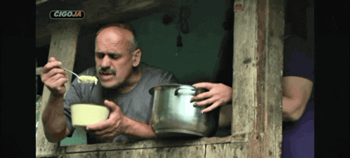 a man is eating from a bowl in front of a sign that says cigaja