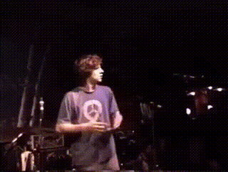 a man in a purple shirt is dancing on a stage in a dark room .