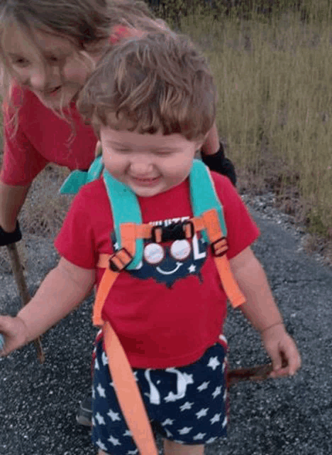 a little boy wearing a red shirt that says " cool " on it