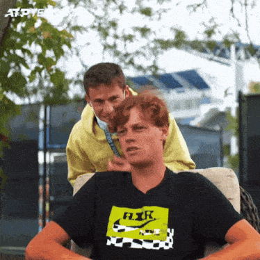 a man wearing a nike t-shirt sits next to another man