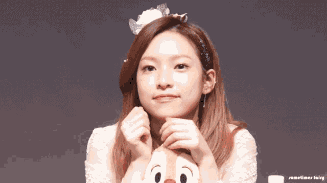 a woman in a white dress is holding a stuffed animal with a disney character on it