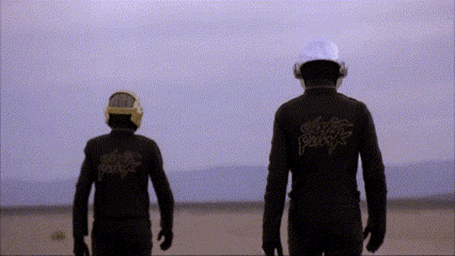 a man wearing a black jacket with the word daft punk on the back is standing next to another man