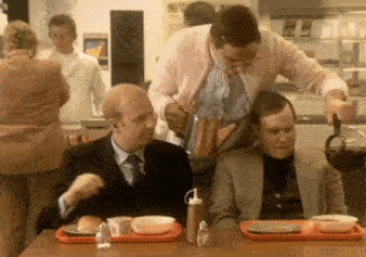 a man in a pink cardigan pours coffee into a man 's cup