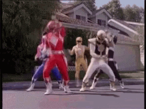 a group of power rangers are dancing on the street .