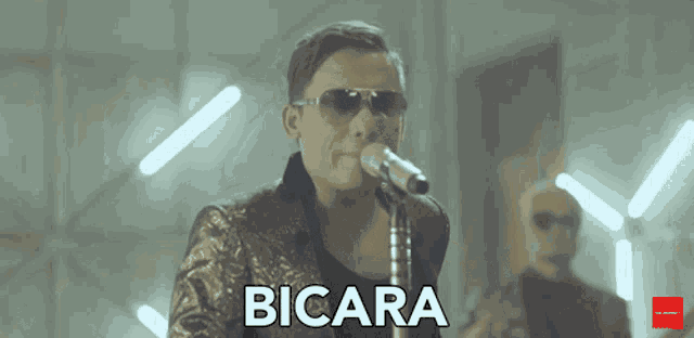 a man singing into a microphone with the word bicara written below him