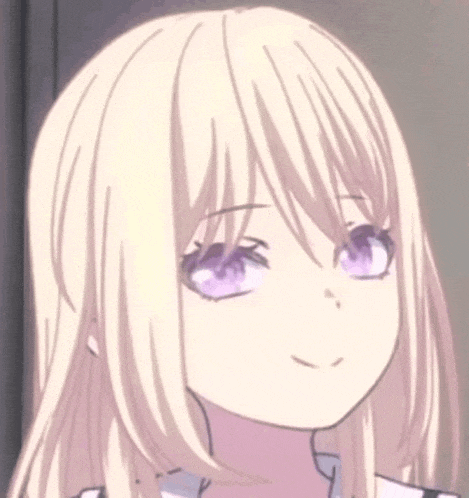 a close up of a girl with blonde hair and purple eyes smiling .
