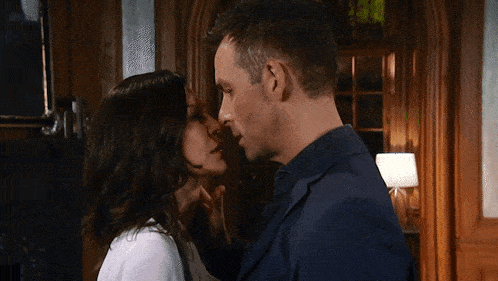 a man and woman are kissing in a room
