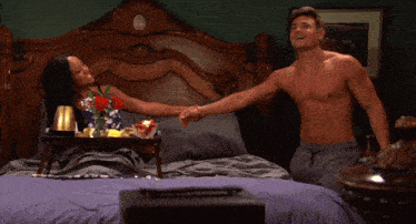 a shirtless man sits on a bed with a woman