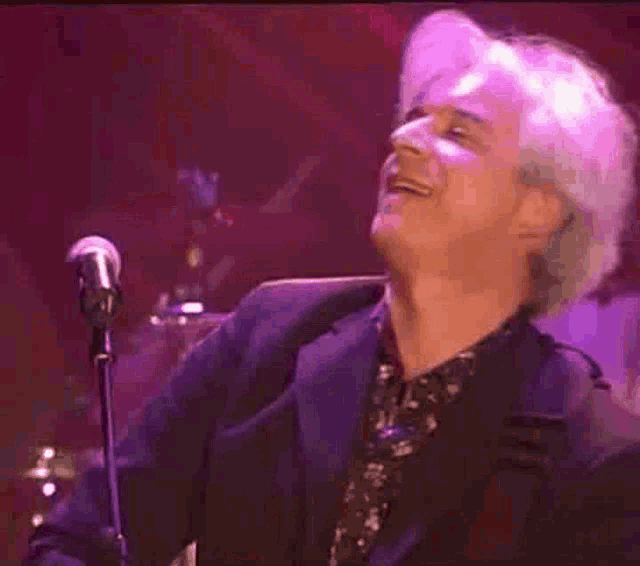 a man is singing into a microphone while playing a guitar