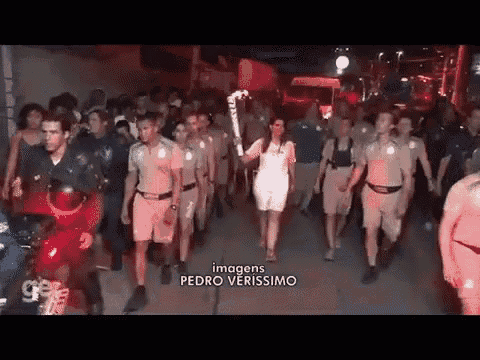 a group of police officers are marching down a street with a woman holding a torch .