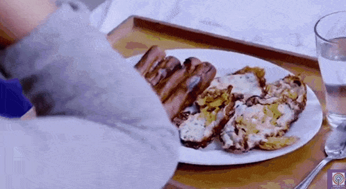 a person is eating a plate of food on a wooden tray .