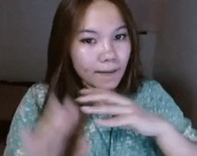 a woman in a blue shirt is making a funny face while holding her hair .