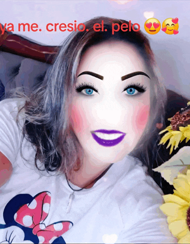 a woman wearing a minnie mouse t-shirt has purple lipstick on