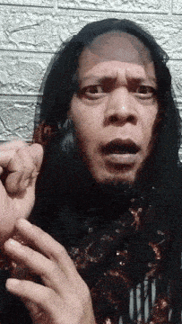 a man with a scarf around his head is making a funny face with his hands