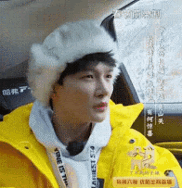 a young man wearing a yellow jacket and a white hat is sitting in a car .