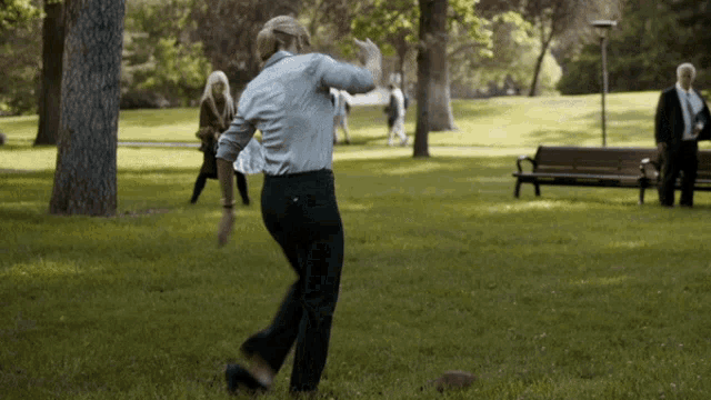 a man in a white shirt and black pants is throwing a ball in the grass