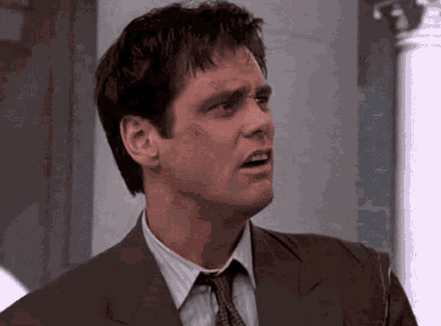 a man in a suit and tie is making a funny face while standing in front of a door .