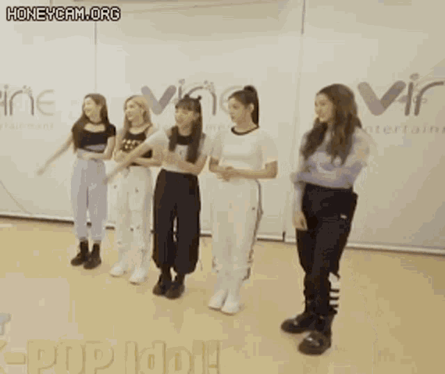 a group of girls are dancing in front of a sign that says ' pop idol '
