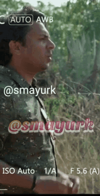 a man in a camouflage shirt is standing in a field with the words auto awb and iso auto written on the bottom