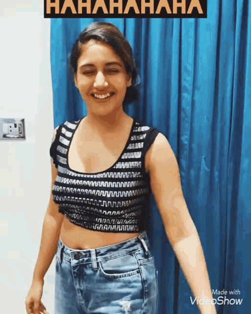 a woman wearing a black and white crop top is smiling in front of a blue curtain that says '  hahaha '