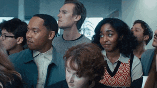 a group of people are sitting in a room looking up at something