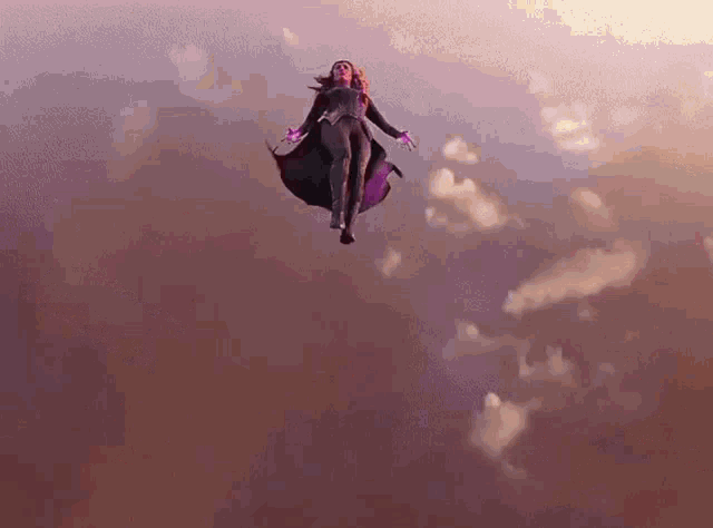 a woman in a superhero costume is flying through the air with her arms outstretched .