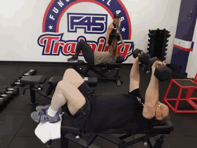 a man is lifting a dumbbell in front of a f45 training sign