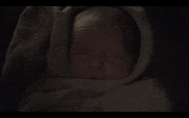 a close up of a baby wrapped in a blanket with its eyes closed .
