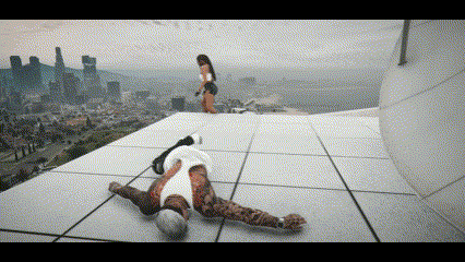a man is laying on the ground on the roof of a building while a woman stands in the background .