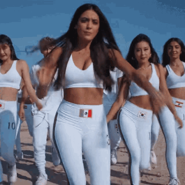 a group of women are walking on a beach and one of them is wearing a number 10 shirt