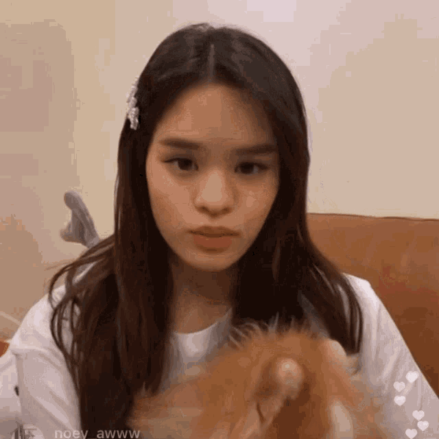 a girl with long hair is wearing a white shirt and holding a stuffed animal in her hand