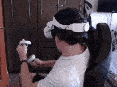 a man wearing an oculus headset is sitting in a chair holding a controller .